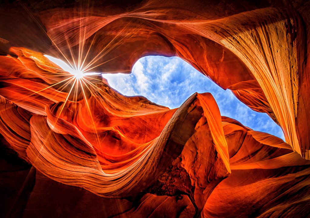 Low-angle view of Antelope Canyon sunlight on red sandstone formations with blue sky background Wallpaper