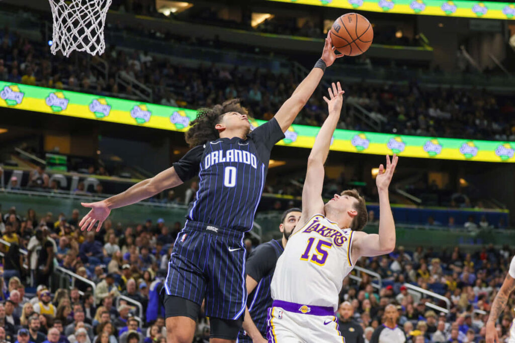 Anthony Black leaps high for a block against Lakers player in intense basketball game action Wallpaper