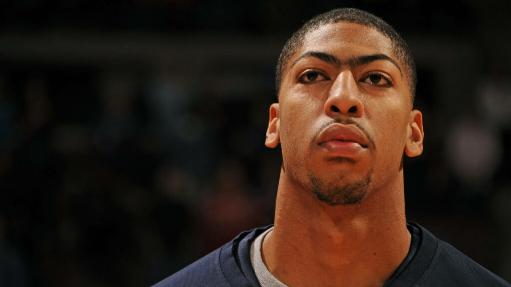 Close-up headshot of Anthony Davis with focused expression and blurred sports background wallpaper