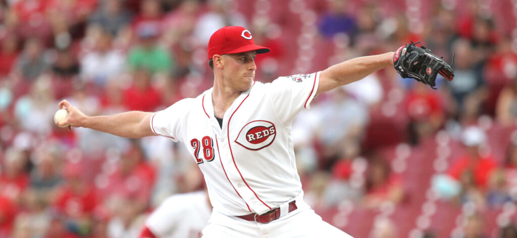Pitcher Anthony DeSclafani in Cincinnati Reds uniform pitching during game with stadium background Wallpaper