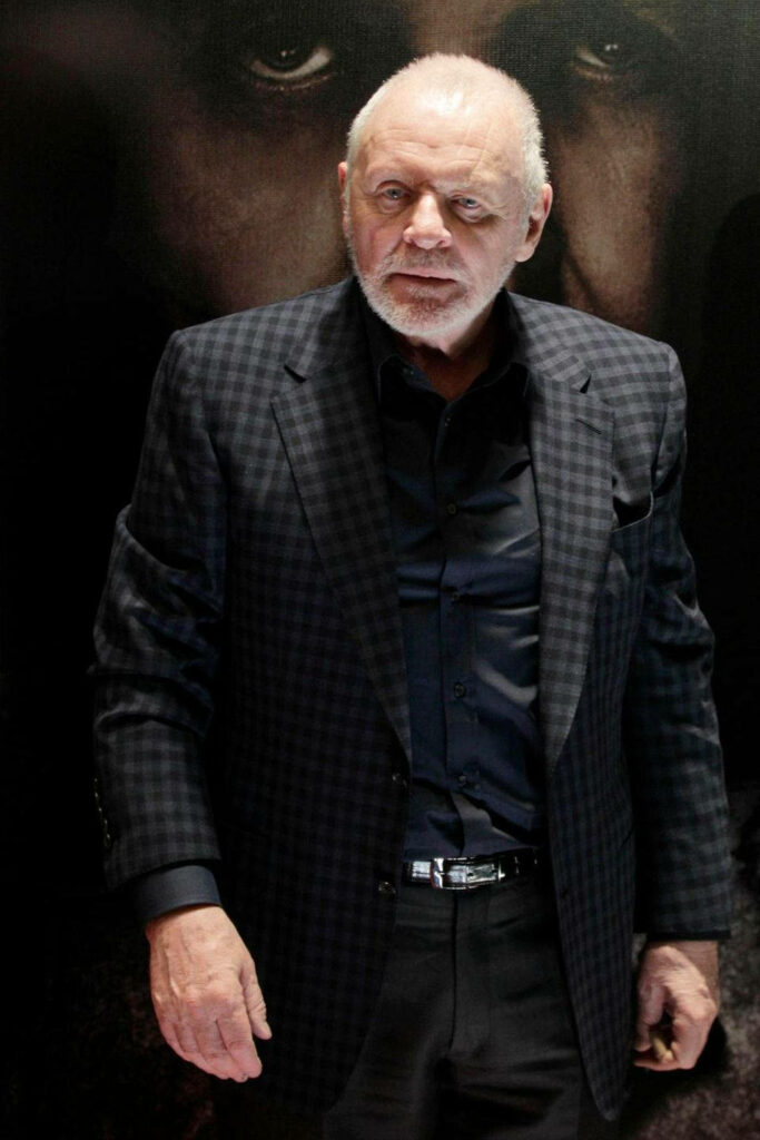 Anthony Hopkins in checkered suit walking confidently dark dramatic background wallpaper