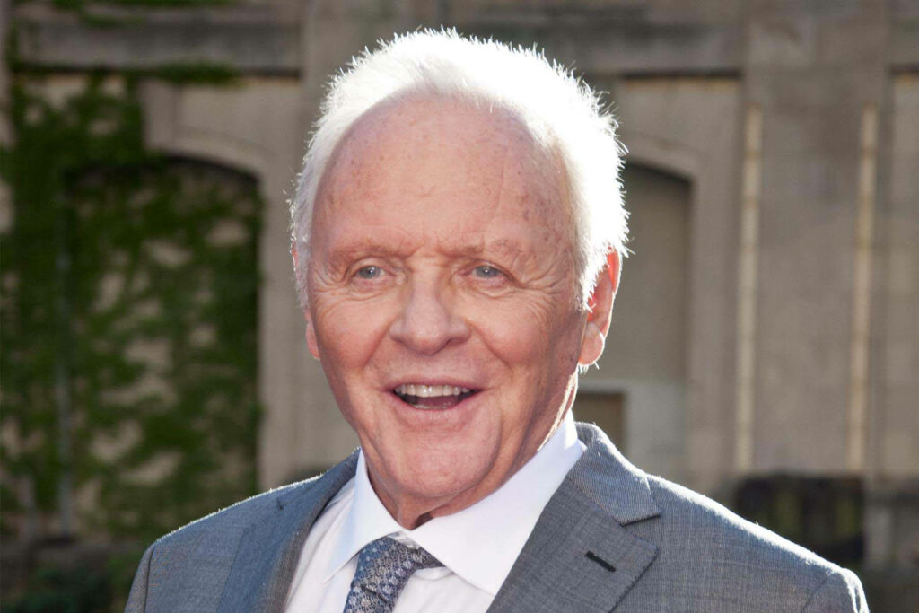 Anthony Hopkins speaking outdoors in light grey suit and patterned tie with warm expression Wallpaper