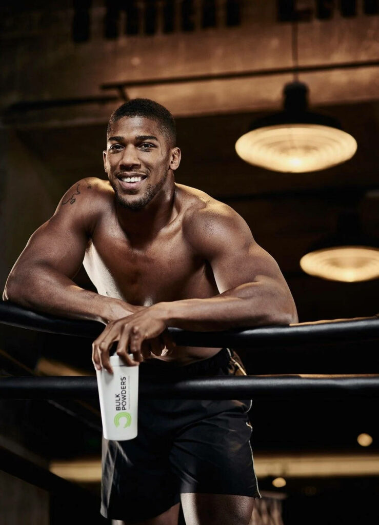 Anthony Joshua smiling confidently leaning on gym ropes showing athletic build wallpaper