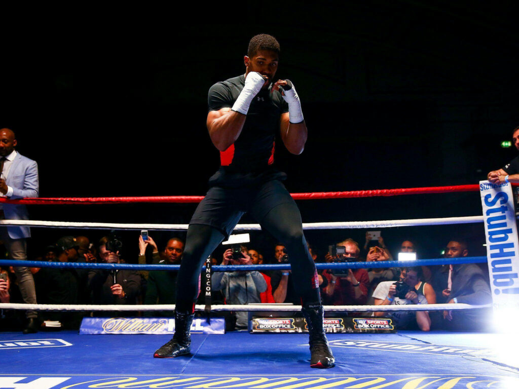 Anthony Joshua in black shirt training with fists raised in boxing ring intense workout wallpaper