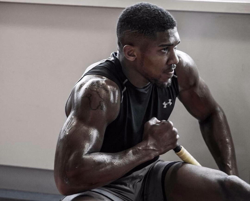 Anthony Joshua showcasing muscular right arm and intense focus in motivational workout wallpaper