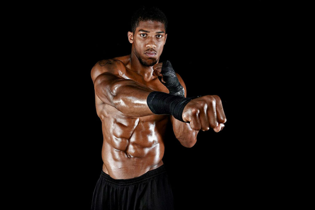 Anthony Joshua shirtless boxing pose showing muscular physique on black wallpaper background