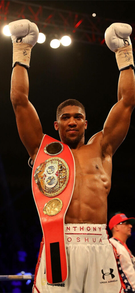 Anthony Joshua victorious in boxing ring with championship belt and raised hands wallpaper background