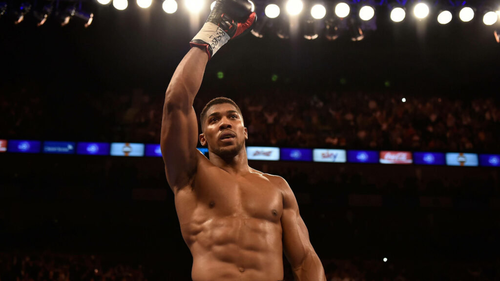 Anthony Joshua victorious in boxing ring under bright lights showing focus and determination Wallpaper