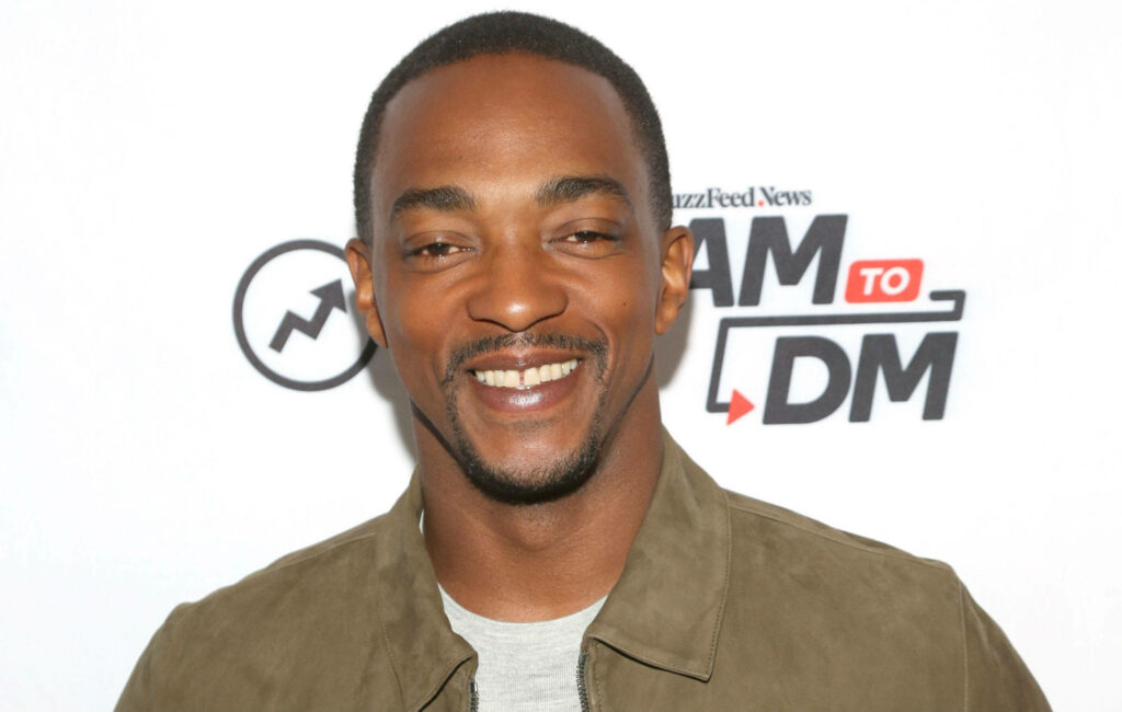 Anthony Mackie beaming with iconic smile at media event charismatic friendly wallpaper background