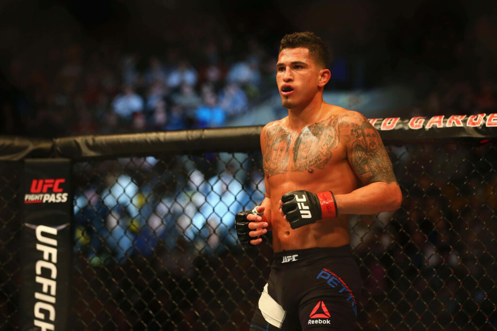 MMA fighter Anthony Pettis focused inside UFC octagon showing athletic physique and tattoos Wallpaper
