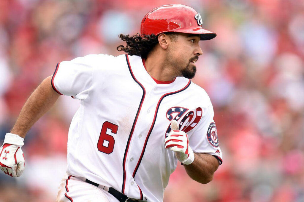 Anthony Rendon running in white baseball uniform focused in vibrant stadium crowd background Wallpaper
