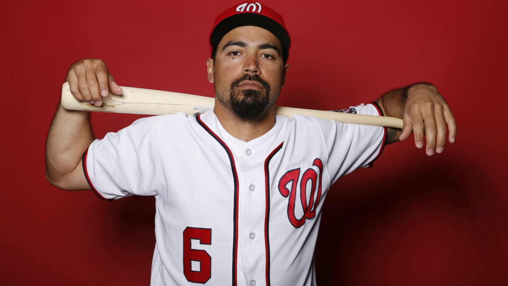 Anthony Rendon in Washington Nationals uniform holding baseball bat against red wallpaper background