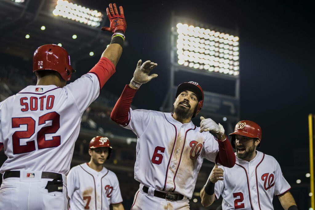 Anthony Rendon and Washington Nationals teammates celebrate with high fives under stadium lights Wallpaper