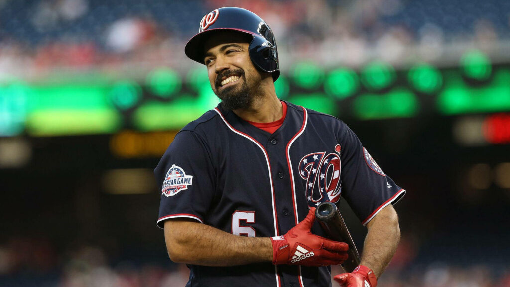 Anthony Rendon in Washington Nationals uniform smiling holding bat on field with bright stadium lights Wallpaper