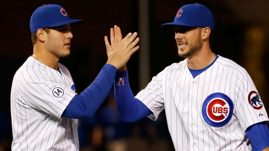 Anthony Rizzo celebrates with teammate high five in Chicago Cubs uniforms on baseball field wallpaper