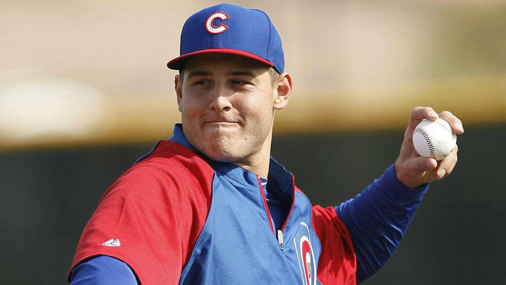 Anthony Rizzo in Chicago Cubs uniform ready to throw baseball during practice with wallpaper background