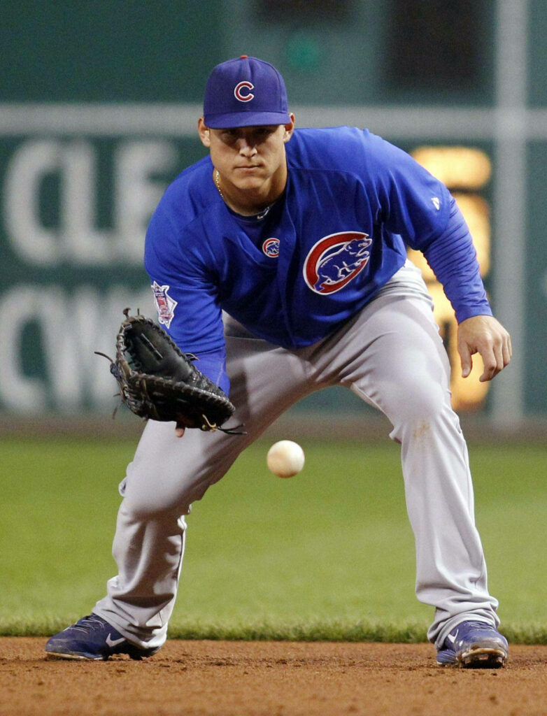 Anthony Rizzo poised to catch baseball in Chicago Cubs uniform on field with wallpaper background