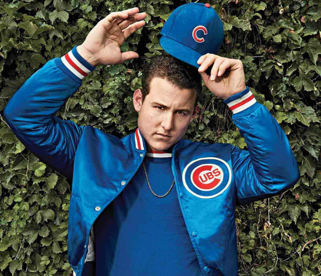 Anthony Rizzo wearing Chicago Cubs jacket holding Cubs hat with green ivy background wallpaper