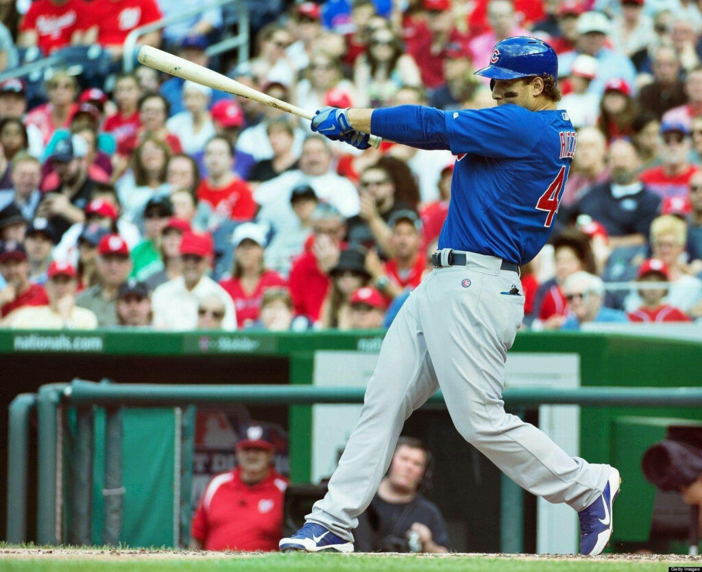 Anthony Rizzo swinging powerfully in blue Chicago Cubs uniform on baseball field action shot Wallpaper