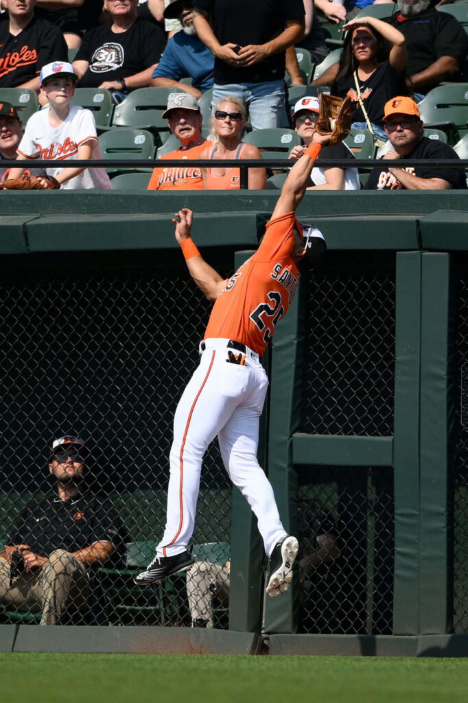 Anthony Santander leaps at outfield wall making impressive baseball catch thrilling excited crowd Wallpaper