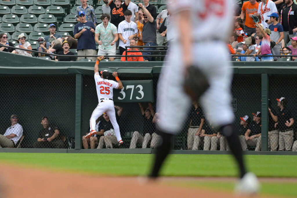 Anthony Santander jumps at outfield wall making a spectacular baseball catch with fans cheering Wallpaper