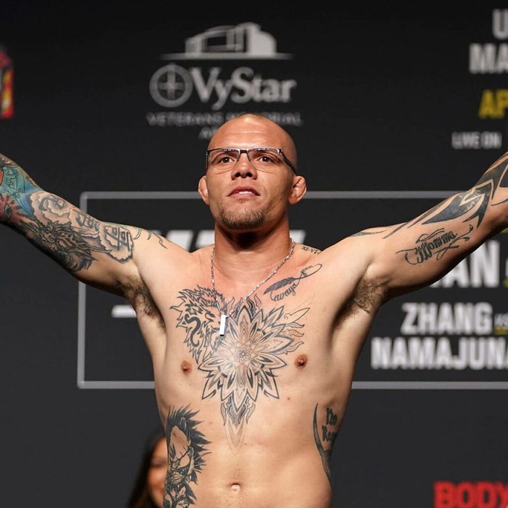 Anthony Smith tattooed fighter raising arms confidently at weigh-in event with sponsor backdrop Wallpaper