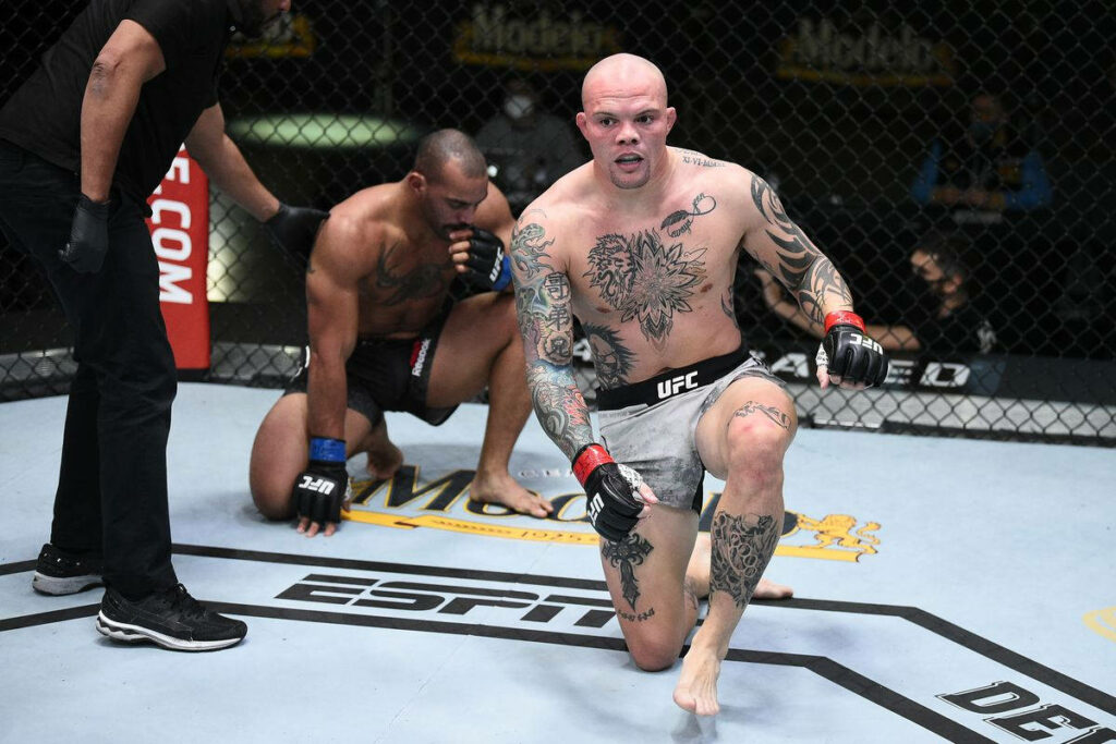 Anthony Smith standing determined in UFC octagon after fierce fight with opponent behind him Wallpaper