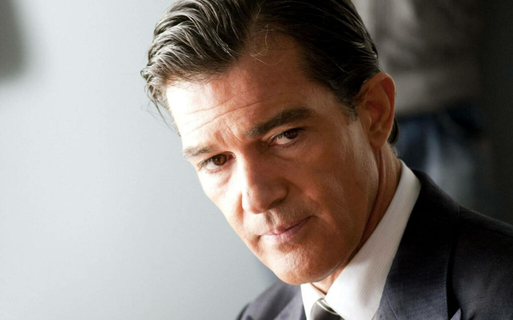Antonio Banderas in formal suit posing confidently exuding charm high resolution wallpaper background