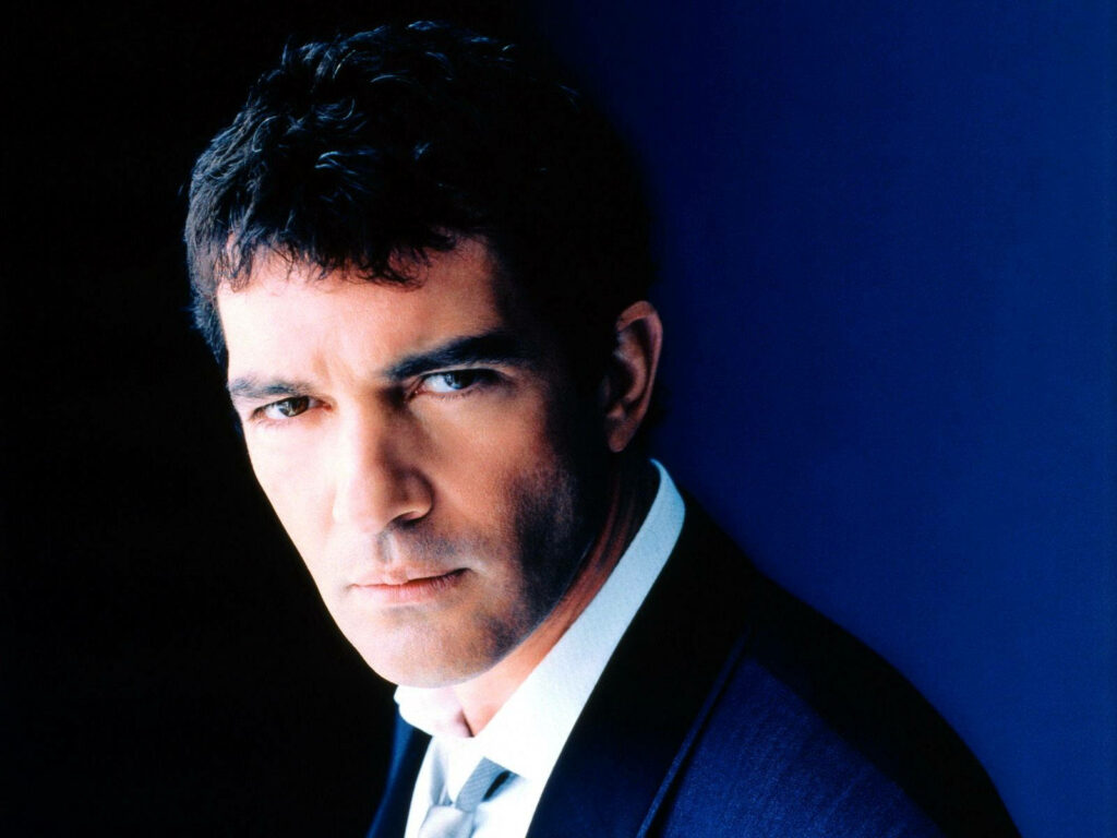 Antonio Banderas sharp suit portrait deep blue background intense charismatic film producer wallpaper