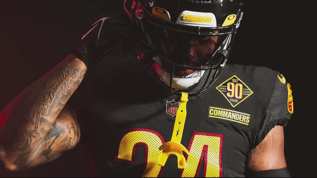 Antonio Gibson in Commanders uniform with detailed tattoos against a dark dramatic background Wallpaper