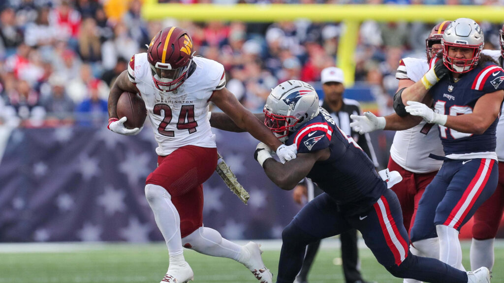 Antonio Gibson evades tackle displaying agility and determination in intense football game wallpaper