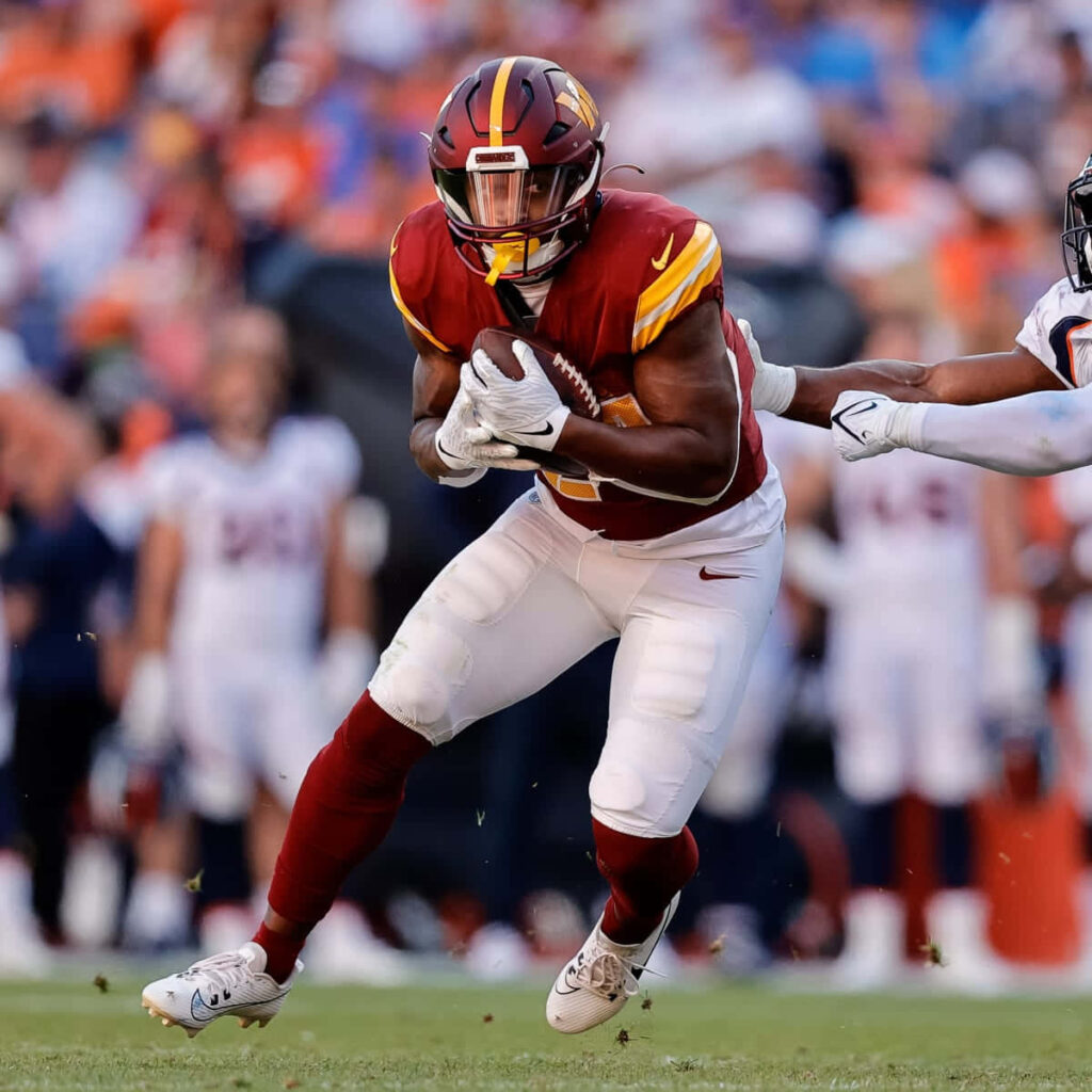 Antonio Gibson sprinting past defenders showcasing speed and determination football action shot Wallpaper
