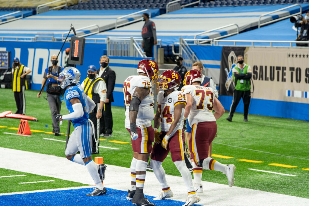 Antonio Gibson celebrates NFL touchdown with teammates during exciting live football game action Wallpaper