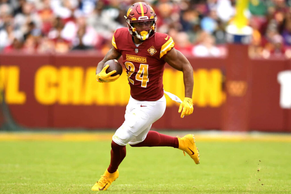 Antonio Gibson running full speed for Washington Commanders showcasing power and agility wallpaper