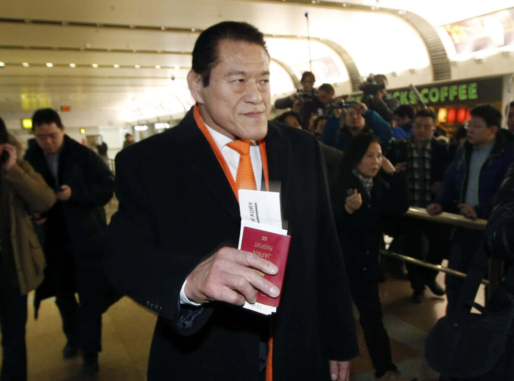 Antonio Inoki at airport holding passport and travel documents surrounded by media photographers Wallpaper