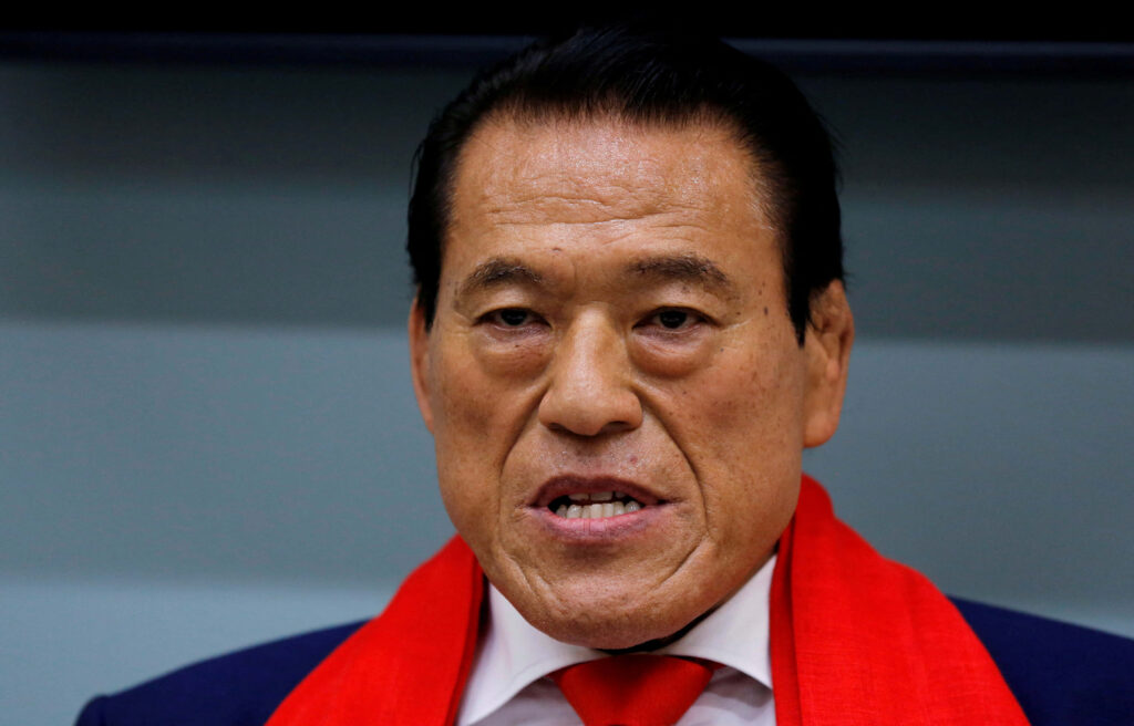 Close-up of Antonio Inoki in formal attire with red scarf against black and gray background wallpaper