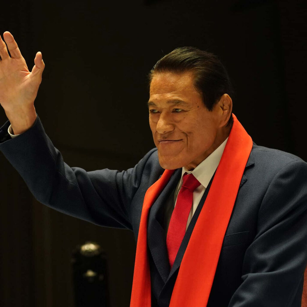 Antonio Inoki in sharp suit and red scarf confidently raising hand iconic wrestling legend wallpaper