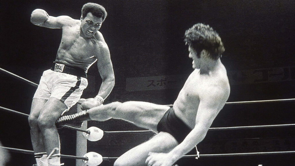 Antonio Inoki executing a powerful kick in an intense wrestling match with dynamic energy Wallpaper