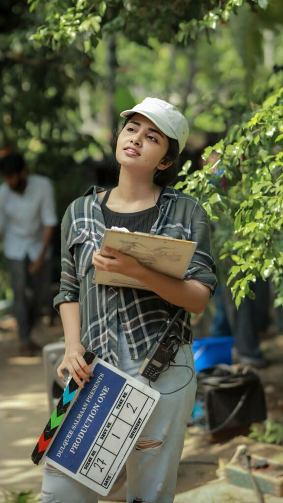 Anupama Parameswaran on film set holding clapperboard with crew in outdoor behind the scenes Wallpaper
