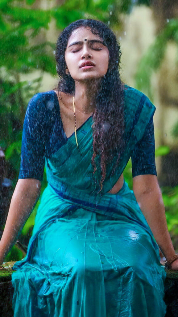 Anupama Parameswaran in blue saree enjoying rain with lush green background wallpaper