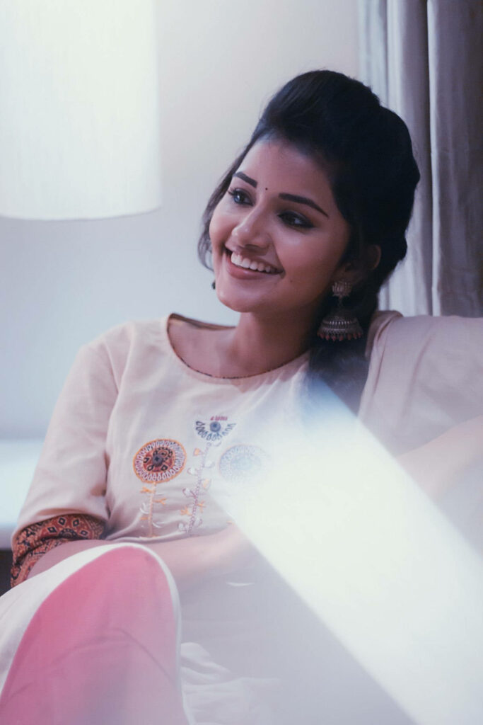 Anupama Parameswaran smiling softly seated relaxed serene setting natural charm wallpaper