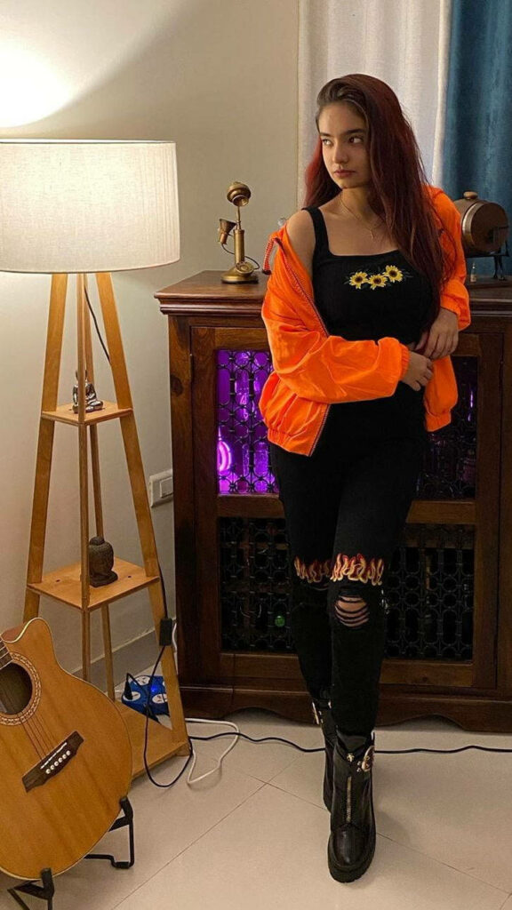 Anushka Sen stylish indoors bright orange jacket black ripped jeans boots trendy fashion look Wallpaper