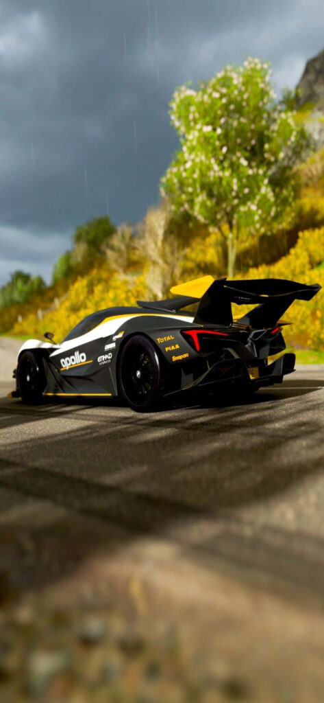 Black and yellow Apollo sports car speeding on scenic road with yellow flowers and green trees Wallpaper