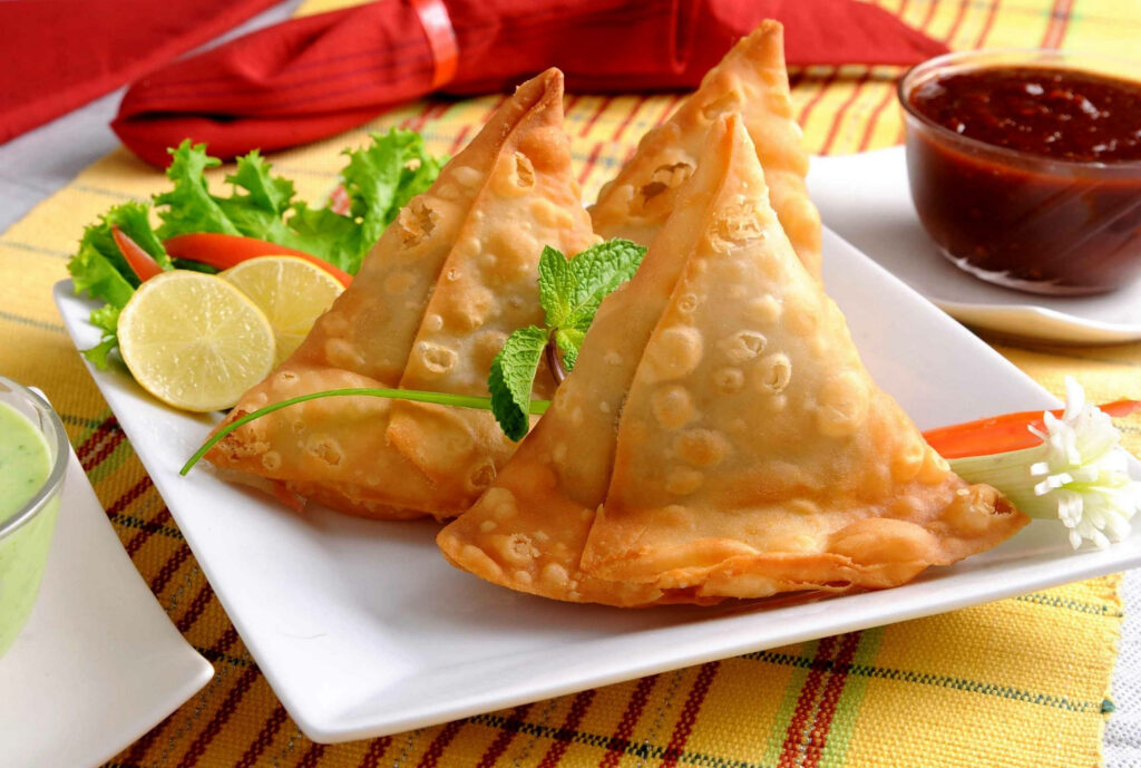 Colorful Close-Up of Crispy Samosas with Mint and Dips - Wallpaper