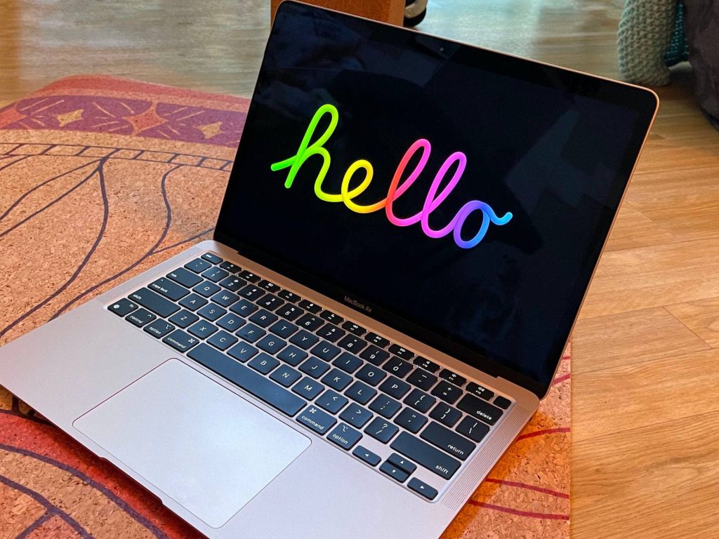 Apple MacBook Air with vibrant rainbow hello wallpaper on black background on textured mat