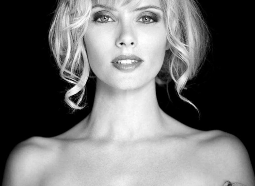 Greyscale photo wallpaper of April Bowlby with dramatic lighting and elegant curls dark background