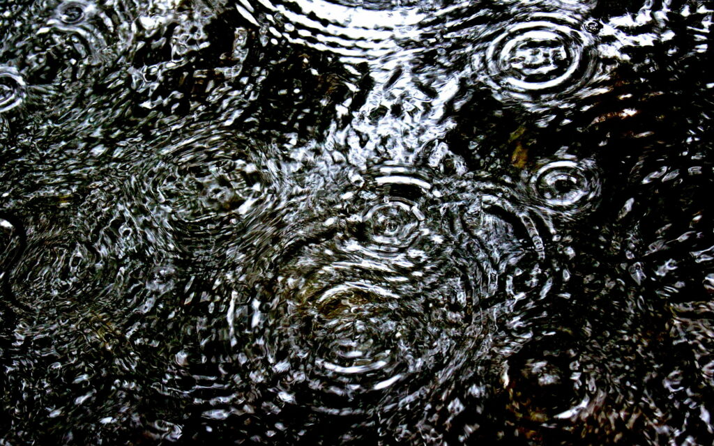 Glistening Water Symphony: Captivating Raindrops on Puddle HD Wallpaper