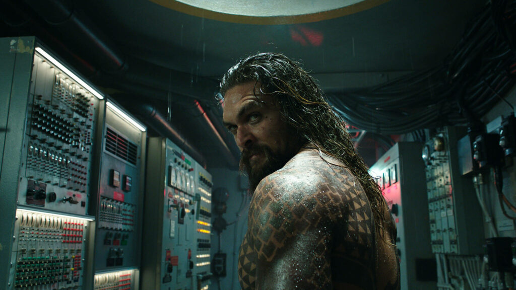 Aquaman in high-tech submarine showing tattoos and intense look wallpaper background