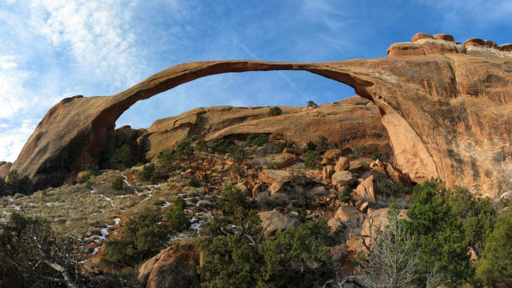 Arches National Park rock arch with rugged red formations under a bright blue sky wallpaper