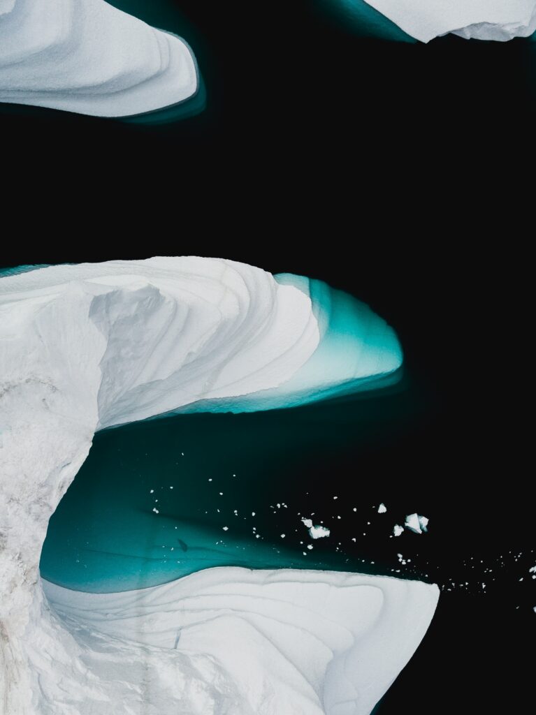 Massive ice floes floating in black water with white snow and turquoise gradients arctic wallpaper